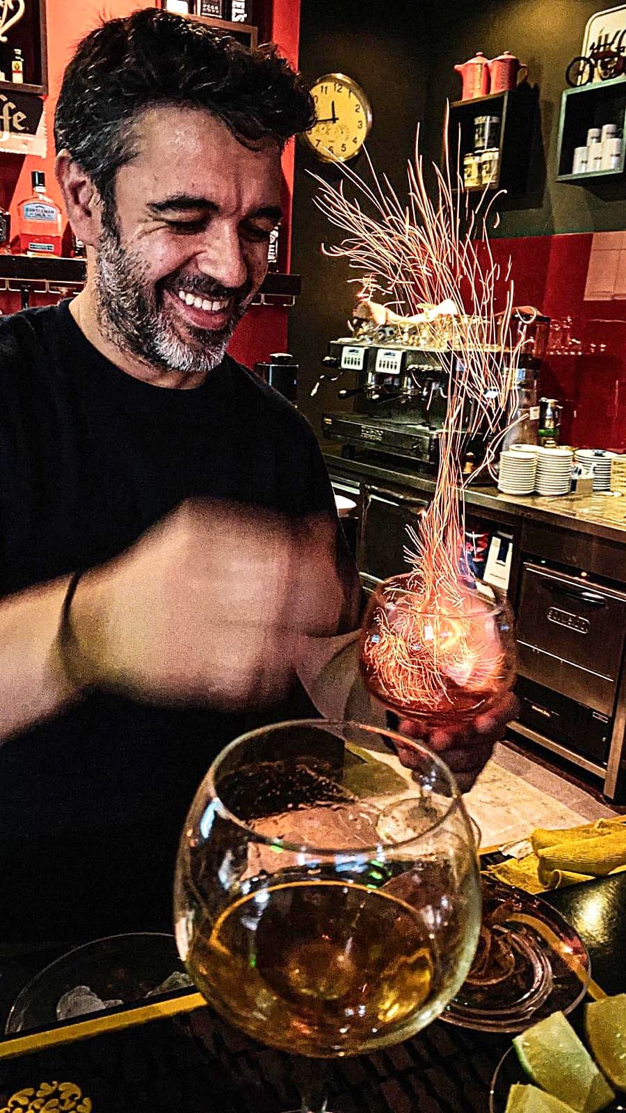 Barman a sorrir enquanto um cocktail lança faíscas no balcão do IKONE