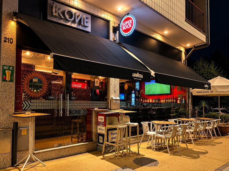 Fachada do IKONE Bar à noite, com a esplanada